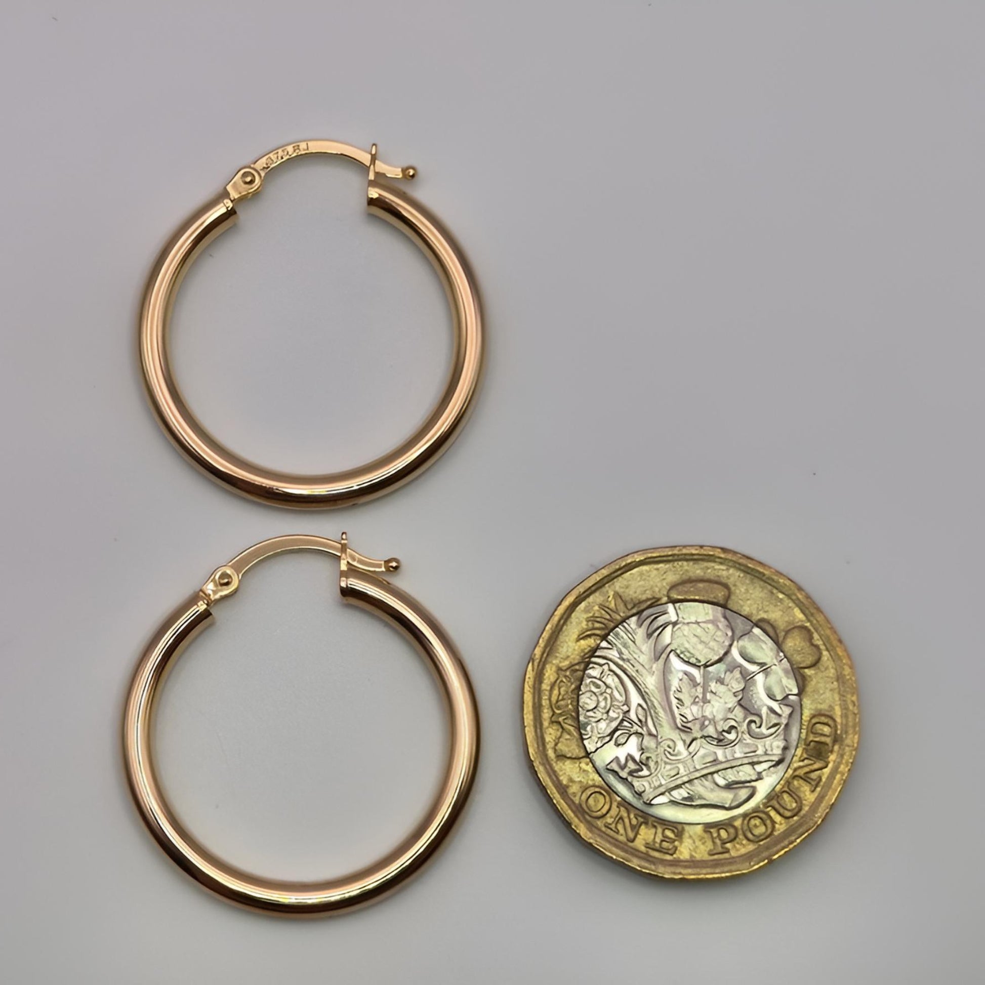 375 gold 20mm hoop earrings next to 1pound coin
