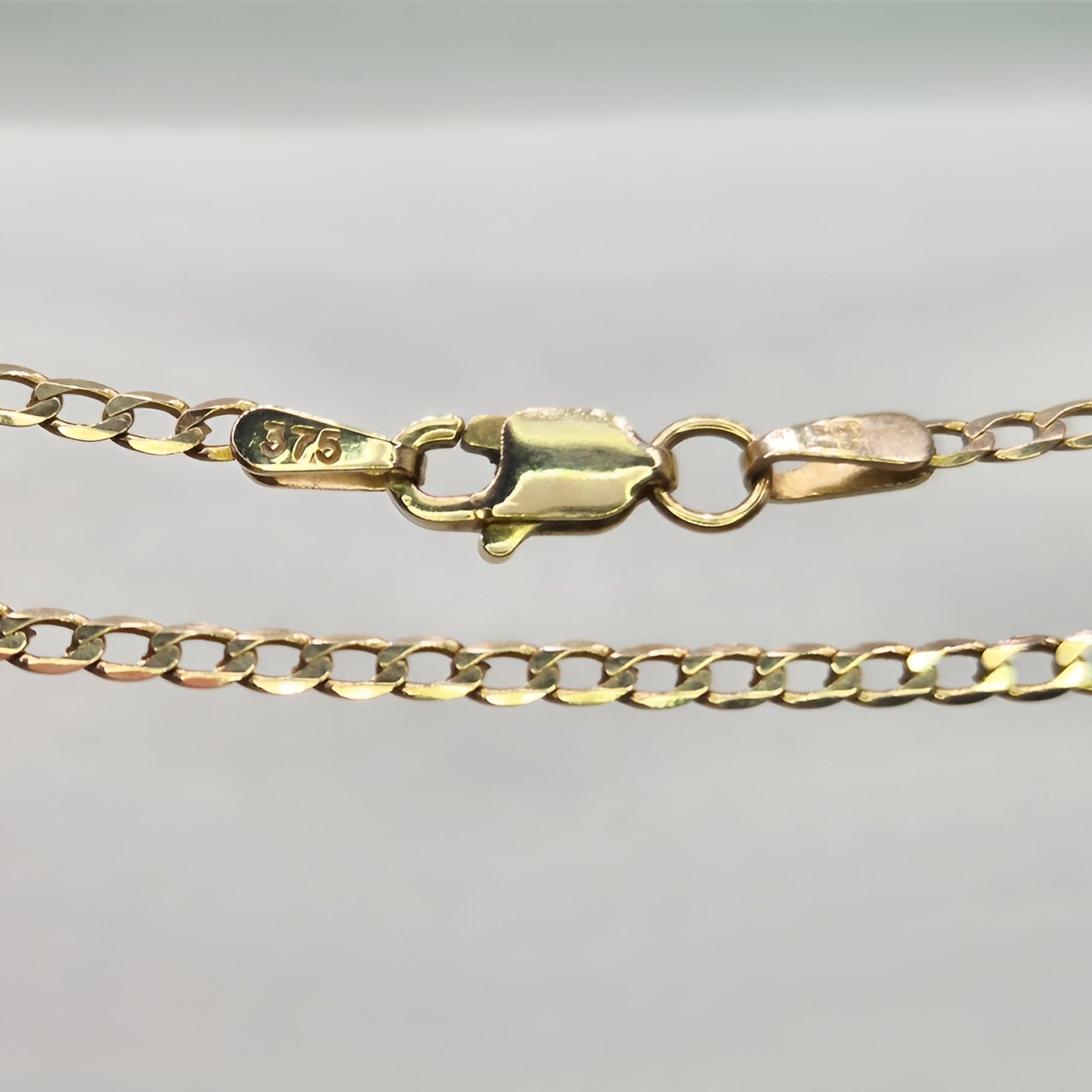 Gold chain with clasp on a light gray background