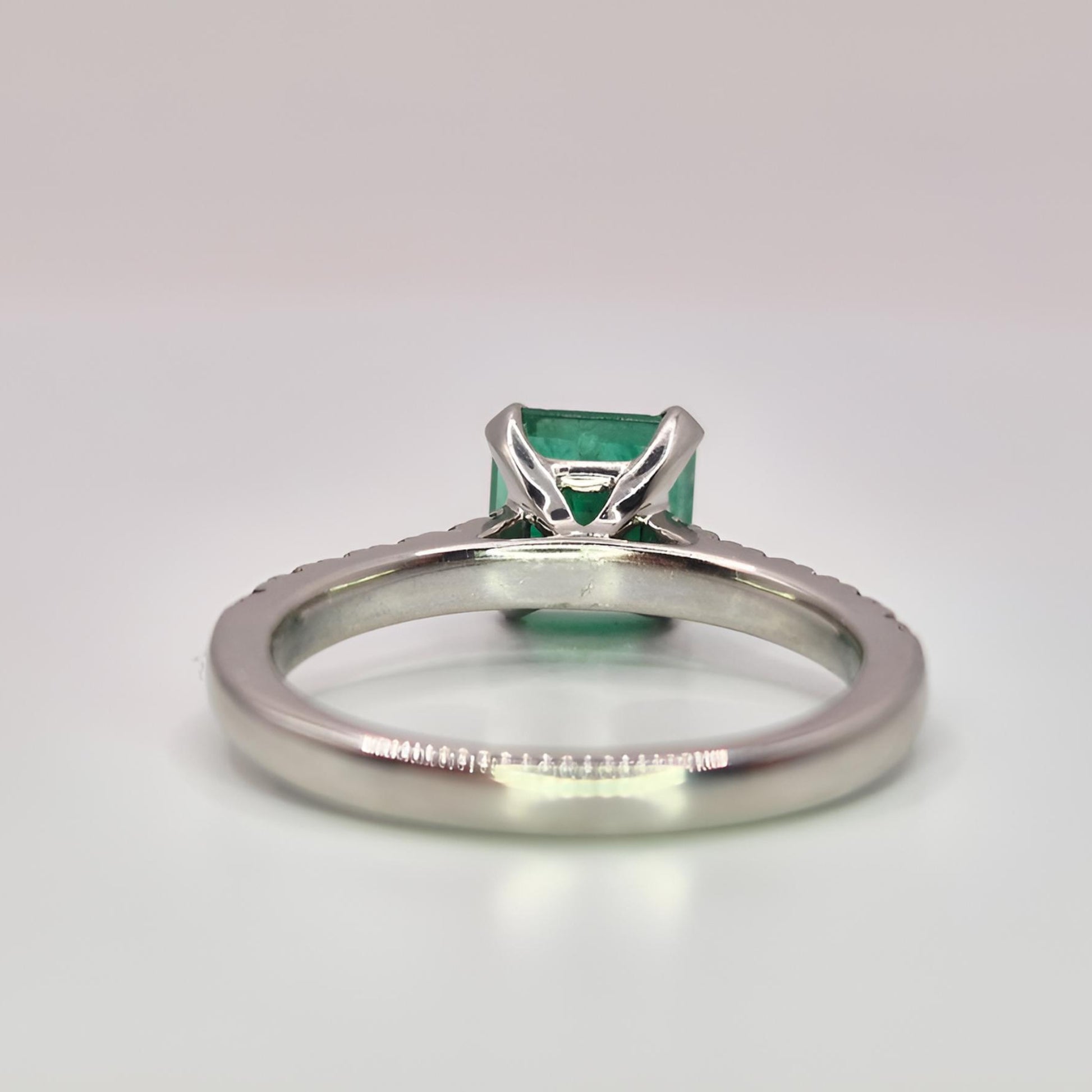 buish green emerald ring behind view