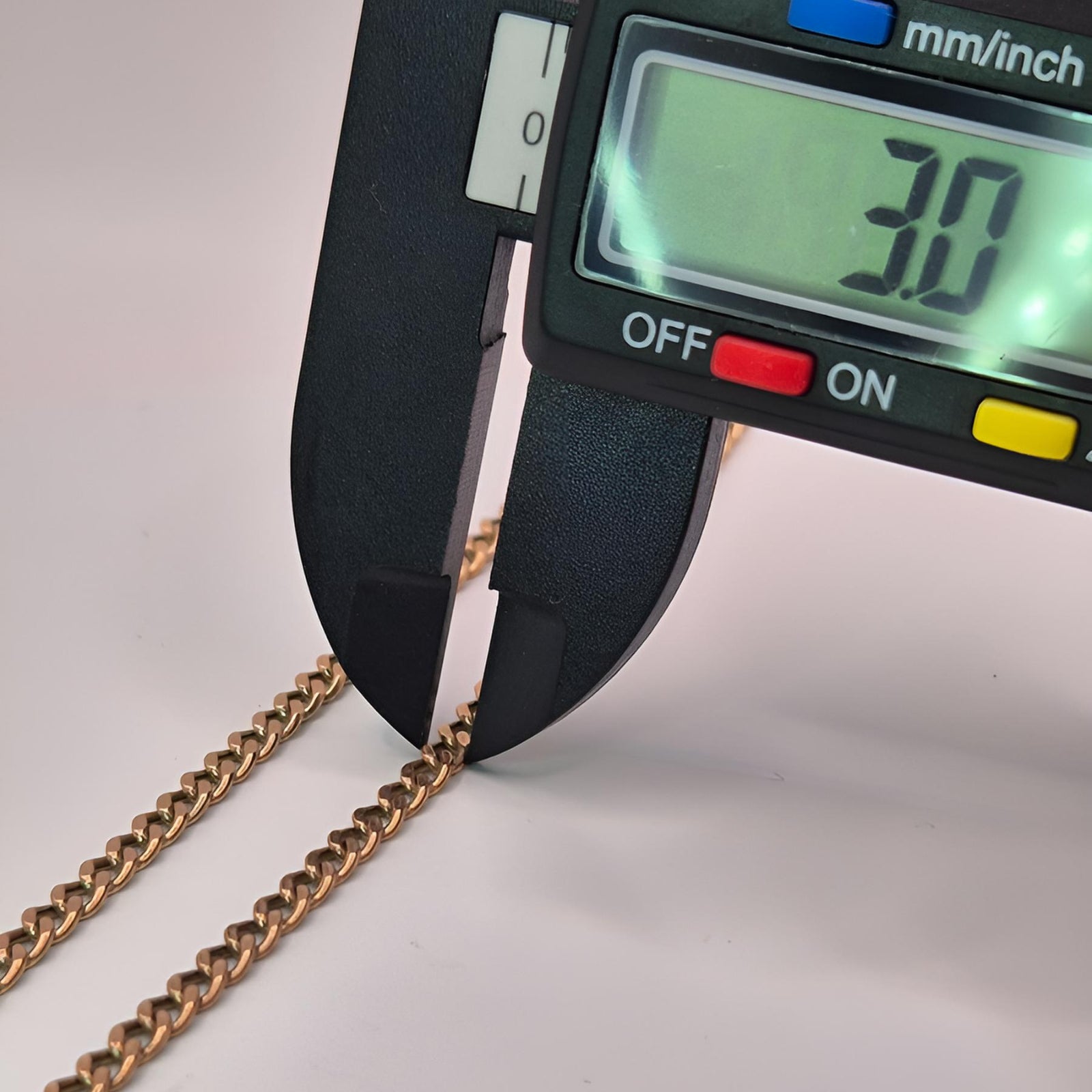 Digital caliper measuring a gold chain with a displayed measurement of 3.0mm.